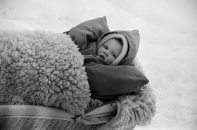 Lapsi makaamassa lampantaljalla vaunuissaan talvella